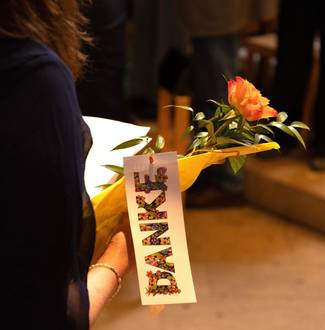 Frau hält gelbe Blume mit Anhänger, auf dem „DANKE“ steht.