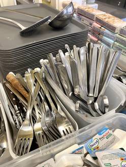 Sortiertes Besteck und gestapelte Teller in einer Cafeteria