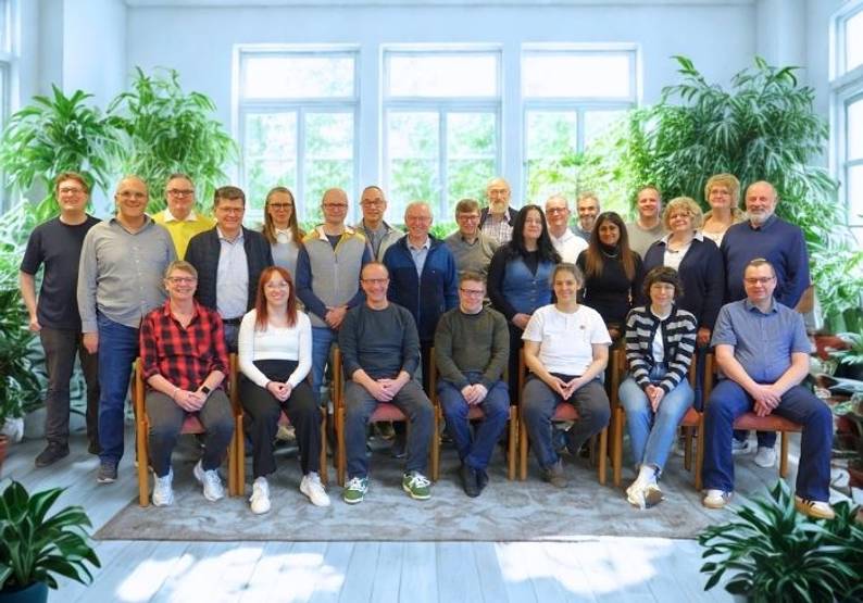 Das Bild zeigt ein Gruppenbild des Pfarreirats in drei Reihen. Der Hintergrund ist hell und es stehen Pflanzen im Raum.