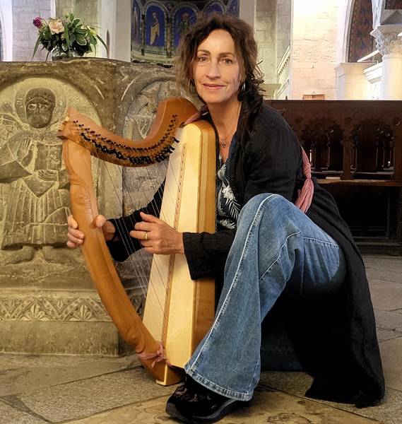 Quelle: Sabine Lindner, Röm.-kath. Kirchengemeinde Sigmaringen KdöR Frau mit langen braunen Haaren sitzt mit Harfe vor einem Altar